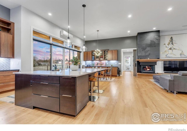 kitchen featuring light wood-style floors, a spacious island, a kitchen breakfast bar, decorative backsplash, and a multi sided fireplace