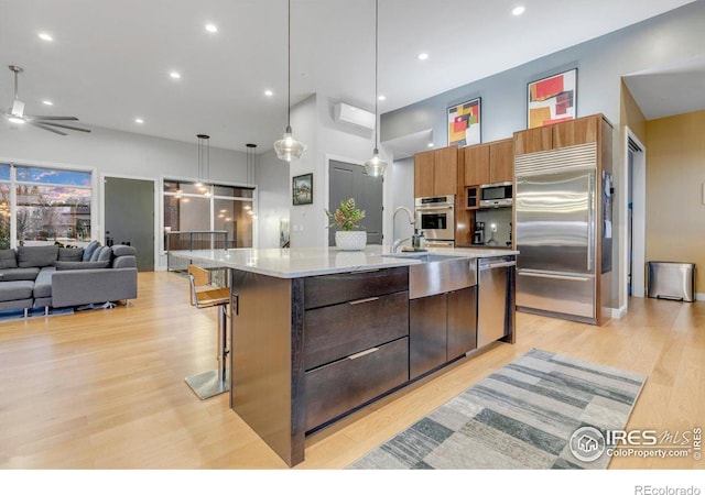 kitchen with appliances with stainless steel finishes, modern cabinets, open floor plan, light countertops, and a ceiling fan