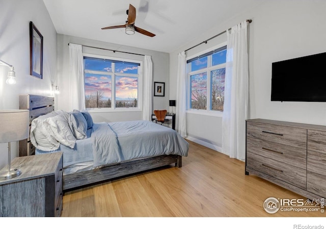 bedroom with light wood-style flooring, ceiling fan, and baseboards