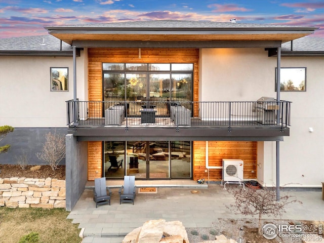 rear view of property with a balcony, ac unit, a patio area, and stucco siding