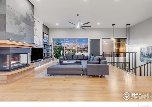 living room with wood finished floors, recessed lighting, a tiled fireplace, and a ceiling fan