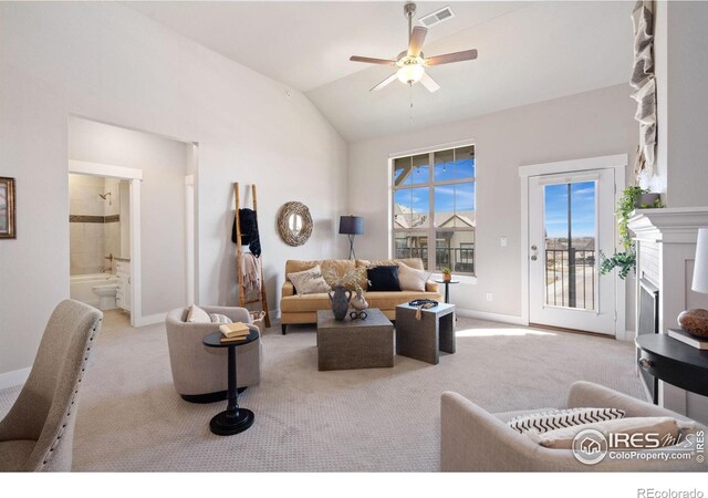 living area featuring visible vents, carpet, vaulted ceiling, a fireplace, and a ceiling fan