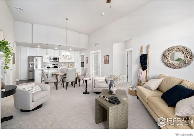 living room featuring visible vents, light carpet, and a high ceiling