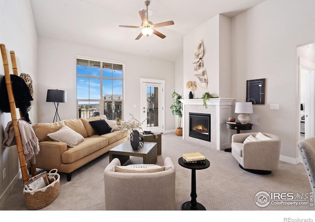 living room featuring baseboards, ceiling fan, a tiled fireplace, carpet floors, and high vaulted ceiling