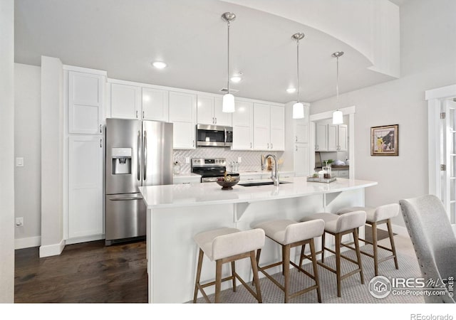 kitchen featuring dark wood-type flooring, a sink, tasteful backsplash, stainless steel appliances, and white cabinets