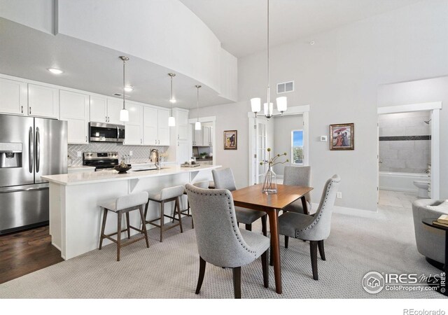 dining room with visible vents, light carpet, baseboards, and a chandelier