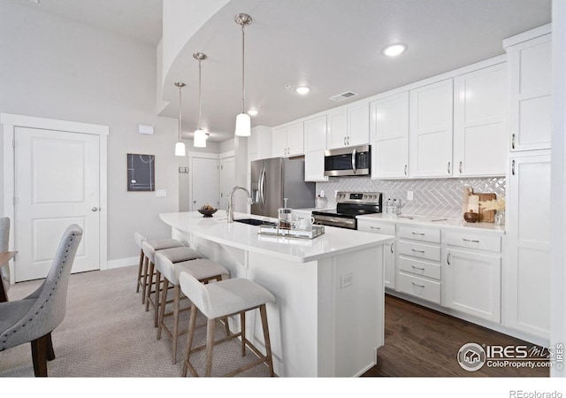 kitchen featuring a sink, backsplash, a breakfast bar area, appliances with stainless steel finishes, and a kitchen island with sink
