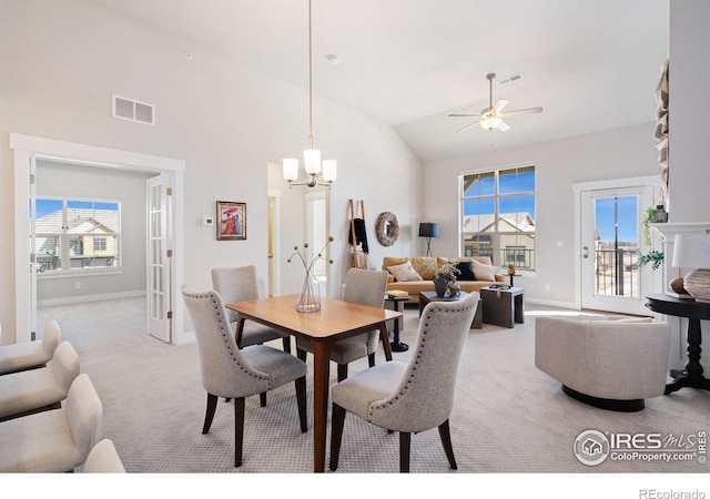 dining space with ceiling fan with notable chandelier, light colored carpet, visible vents, and a wealth of natural light