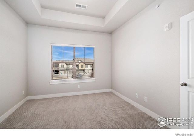 carpeted empty room with a raised ceiling, baseboards, and visible vents