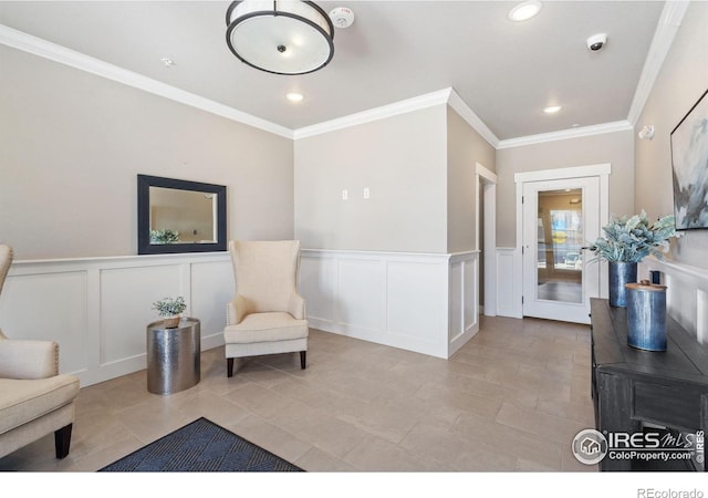 living area featuring recessed lighting, ornamental molding, wainscoting, and a decorative wall