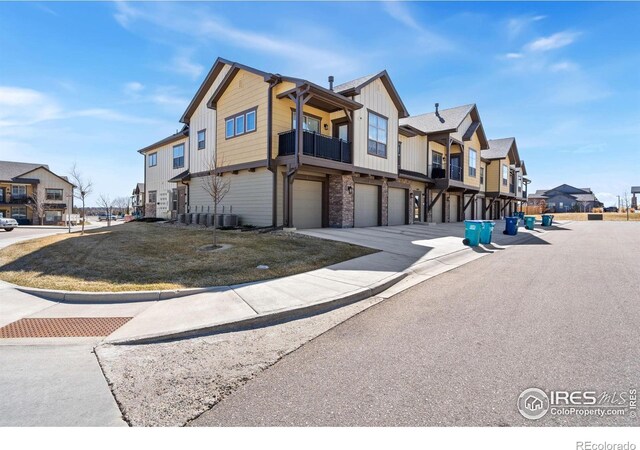 view of home's exterior featuring board and batten siding, a residential view, a lawn, driveway, and an attached garage
