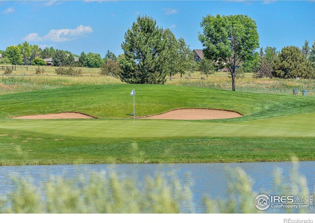 surrounding community with view of golf course, a yard, and a water view