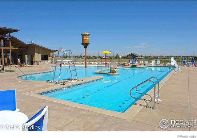 pool with a patio, fence, and a water play area