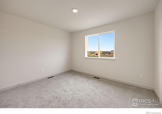 carpeted spare room with visible vents and baseboards