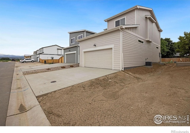 view of side of property with central AC unit, driveway, and fence