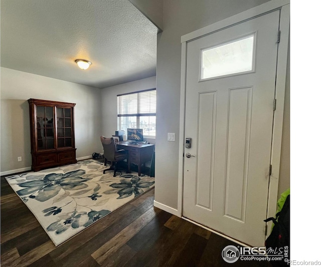 foyer entrance featuring dark wood finished floors, baseboards, and a textured ceiling