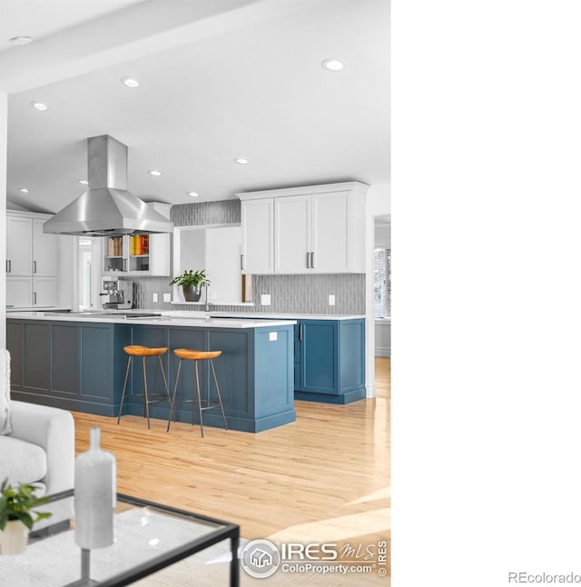 3380 Longwood Ave, Boulder, CO 80305 - kitchen with a breakfast bar area, decorative backsplash, light countertops, white cabinetry, and island range hood
