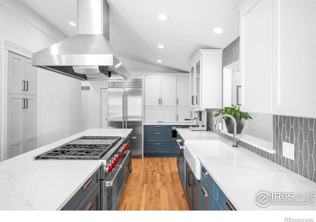3380 Longwood Ave, Boulder, CO 80305 - kitchen with high end appliances, island exhaust hood, white cabinetry, blue cabinets, and tasteful backsplash