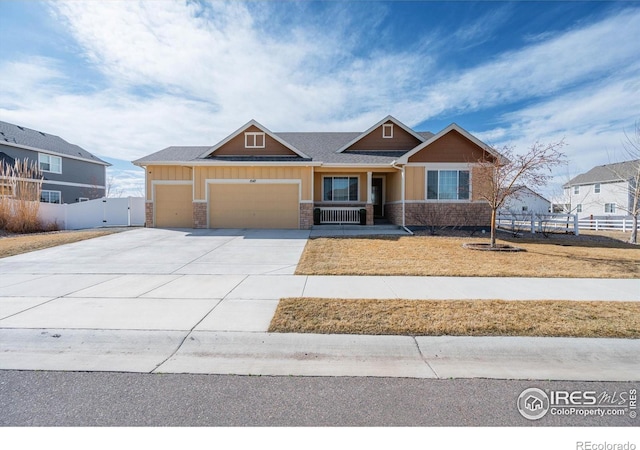 craftsman inspired home featuring an attached garage, fence, stone siding, and driveway