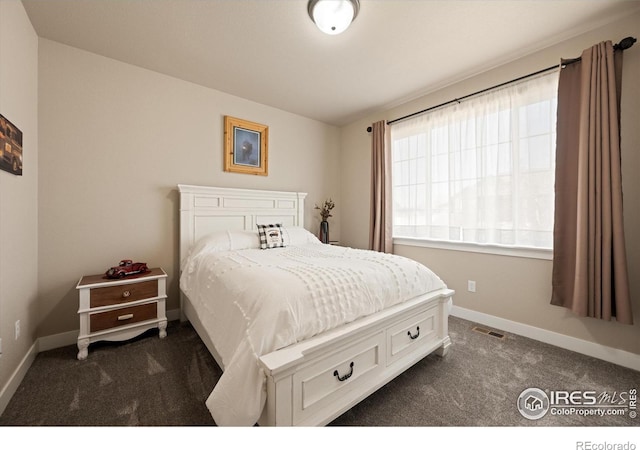 bedroom featuring dark colored carpet and baseboards