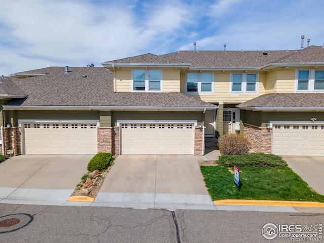 multi unit property featuring an attached garage, a shingled roof, and driveway