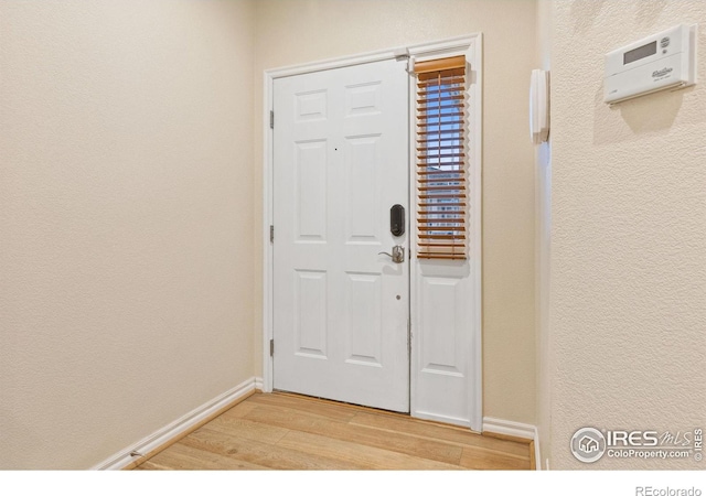 entrance foyer with light wood-style floors, baseboards, and a textured wall
