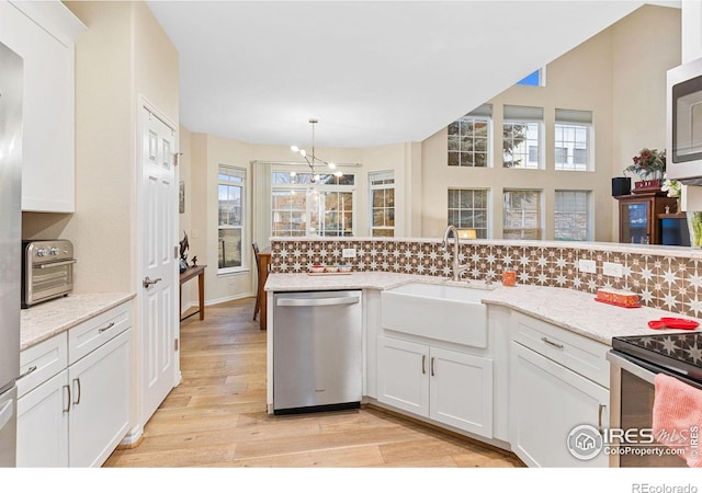 kitchen with a sink, decorative backsplash, stainless steel appliances, and light wood-type flooring