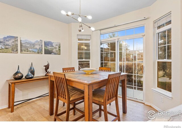 dining space featuring light wood-type flooring, baseboards, a mountain view, and an inviting chandelier