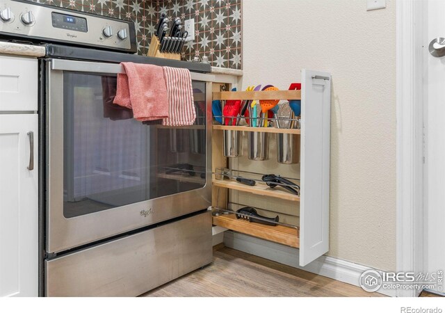 interior details featuring electric range, baseboards, and wood finished floors