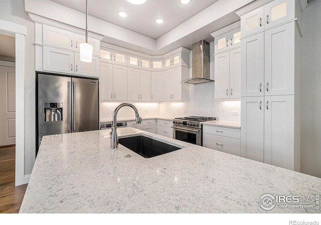 4300 Ardglass Ln, Timnath, CO 80547 - kitchen with wall chimney range hood, appliances with stainless steel finishes, a sink, light stone counters, and hanging light fixtures