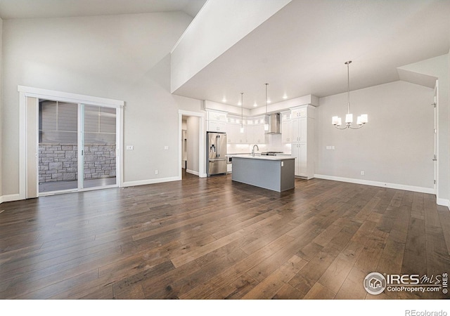 4300 Ardglass Ln, Timnath, CO 80547 - unfurnished living room with a chandelier, dark wood-style floors, a sink, baseboards, and lofted ceiling