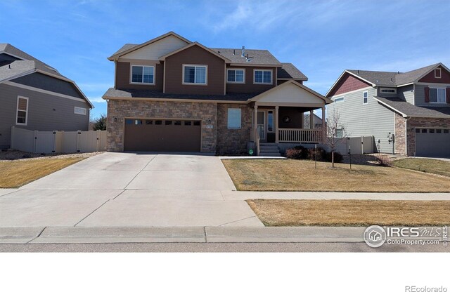 view of front of house with a gate, covered porch, concrete driveway, a garage, and stone siding