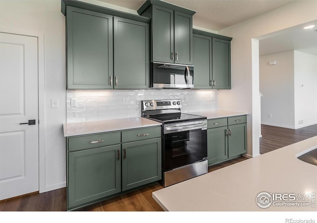 kitchen featuring decorative backsplash, stainless steel appliances, light countertops, and green cabinets