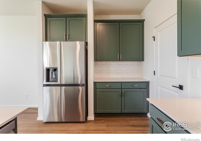 kitchen with wood finished floors, green cabinetry, and stainless steel appliances
