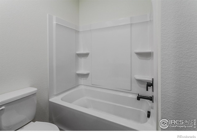 full bath featuring toilet and a textured wall