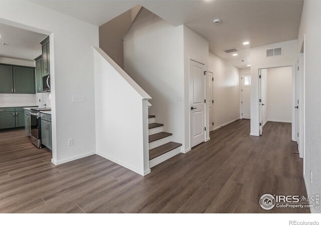 hallway featuring stairway, visible vents, and wood finished floors