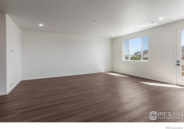 spare room featuring recessed lighting, baseboards, and dark wood-style flooring