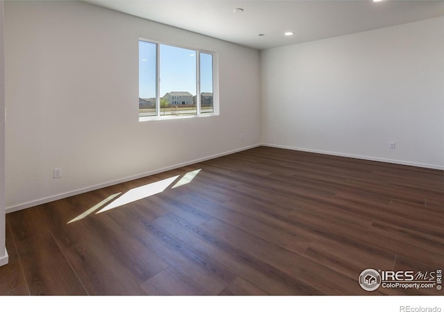 spare room with baseboards, wood finished floors, and recessed lighting