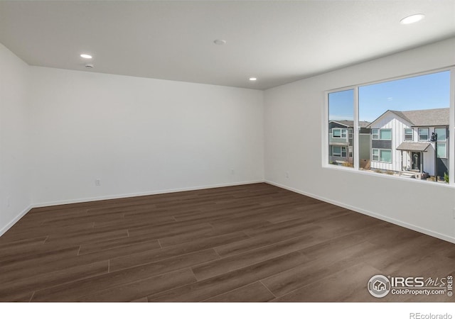 spare room featuring dark wood-type flooring, baseboards, and recessed lighting