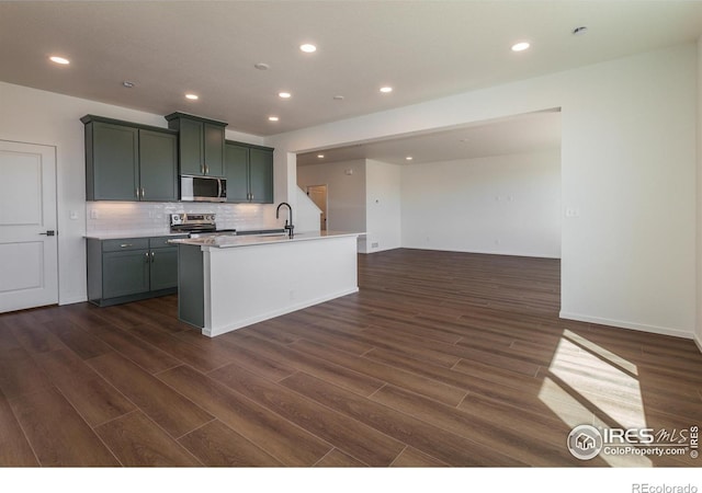 kitchen with decorative backsplash, appliances with stainless steel finishes, light countertops, dark wood-style flooring, and recessed lighting