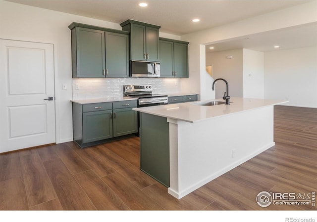kitchen featuring stainless steel appliances, a sink, dark wood-style flooring, backsplash, and green cabinets