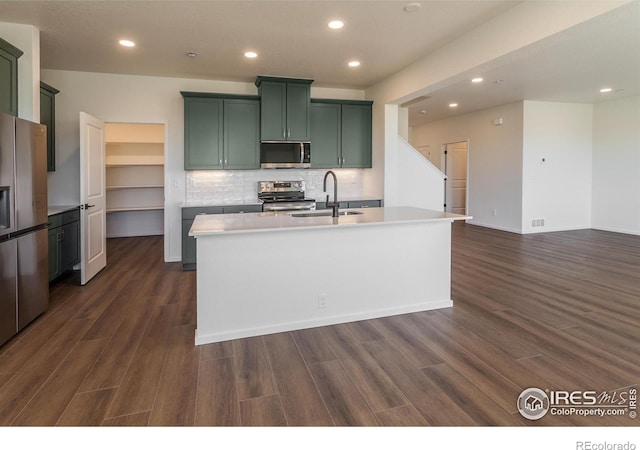 kitchen featuring recessed lighting, green cabinets, stainless steel appliances, and a sink