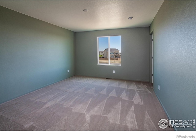 carpeted spare room featuring baseboards
