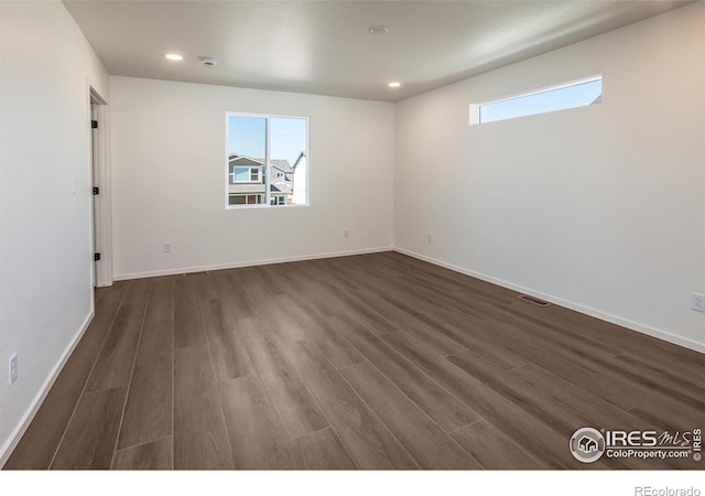 spare room with dark wood finished floors, baseboards, visible vents, and recessed lighting