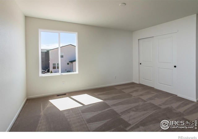 unfurnished bedroom featuring visible vents, baseboards, carpet flooring, and a closet