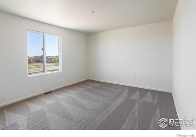 carpeted spare room with visible vents and baseboards