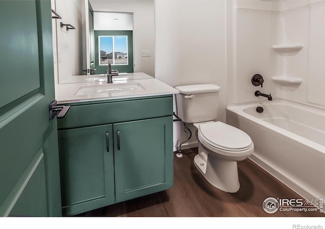 full bath with toilet, wood finished floors, shower / bathing tub combination, vanity, and baseboards
