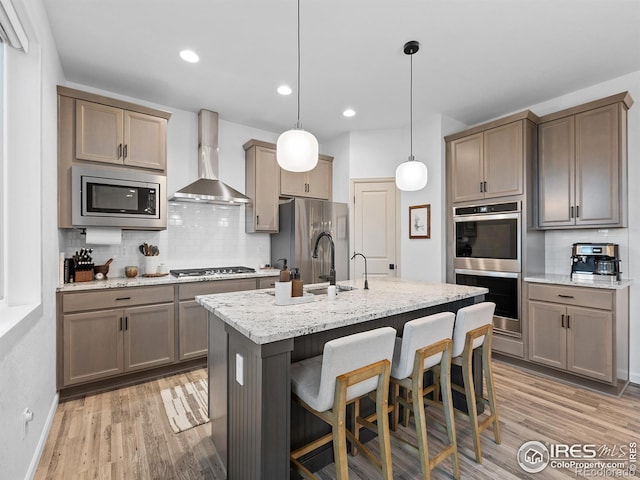 2412 Cottongrass Ave, Loveland, CO 80538 - kitchen featuring wall chimney range hood, light wood-style floors, a sink, and stainless steel appliances