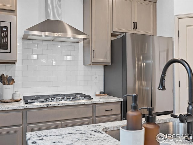 2412 Cottongrass Ave, Loveland, CO 80538 - kitchen featuring gray cabinetry, wall chimney range hood, backsplash, and appliances with stainless steel finishes