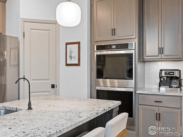 2412 Cottongrass Ave, Loveland, CO 80538 - kitchen with a sink, double oven, light stone counters, backsplash, and freestanding refrigerator